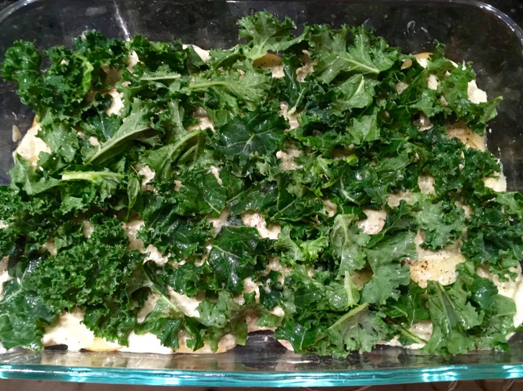 An image of a potato and kale casserole in a glass dish.