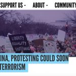 A screen shot of the Feministing website. An article title is shown on the screen. The title reads "In North Carolina, Protesting Could Soon Be Considered Terrorism" in all capital letters. Above that is an image of signs made by protesters. Next to the image is a continuation of the site's navigational bar.