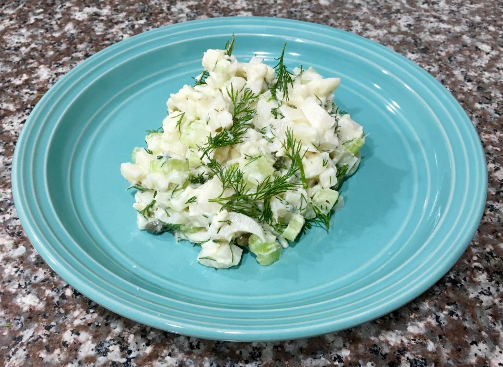 A blue plate with hearts of palm salad on a marble counter.