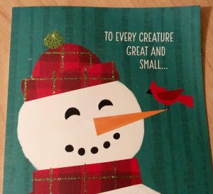 An image of a card reading "To every creature great and small..." with a snowman wearing a red scarf and hat with a red bird on his carrot nose.
