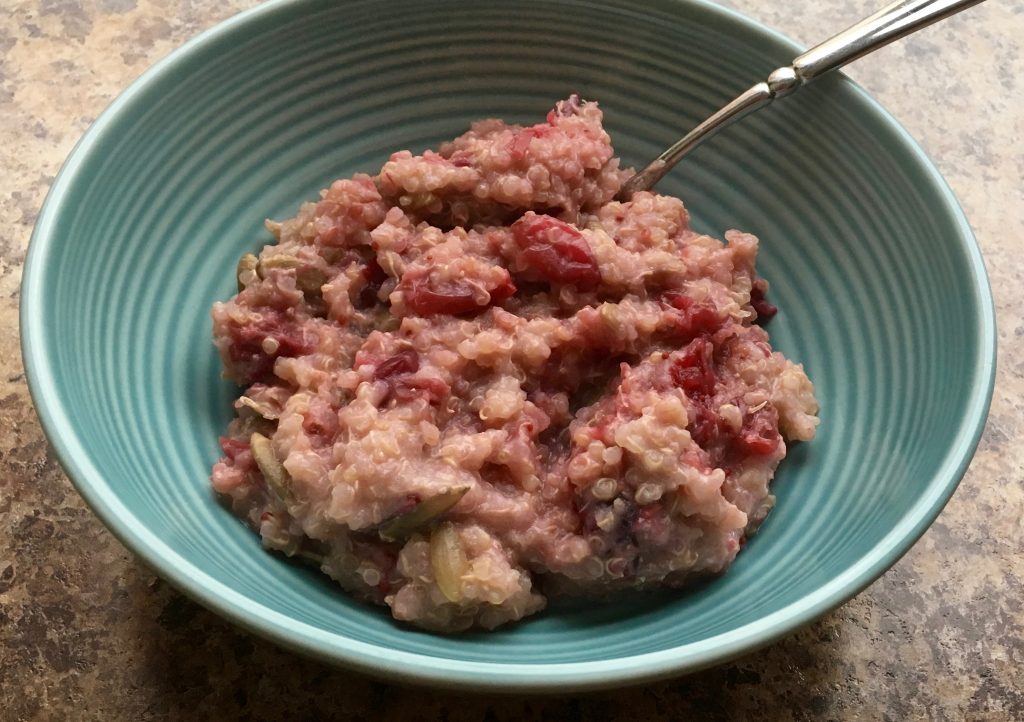 A blue bowl containing warm quinoa cranberry breakfast cereal.