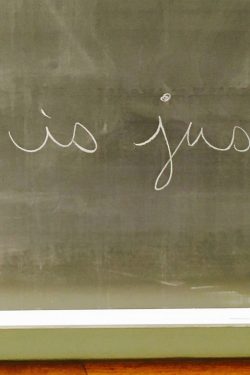"What is justice?" written in white chalk on a black chalkboard.