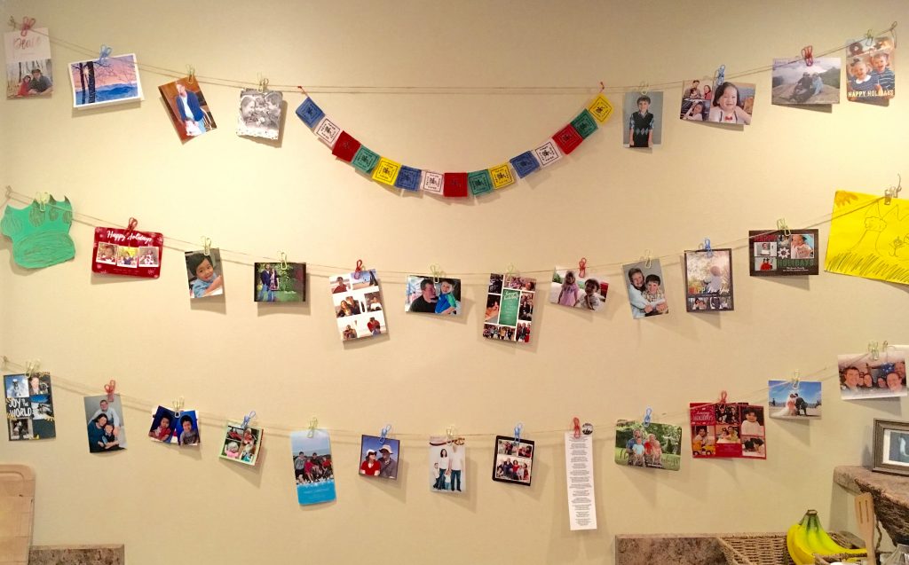 View of my kitchen wall with photos, poetry, artwork, and prayer flags.