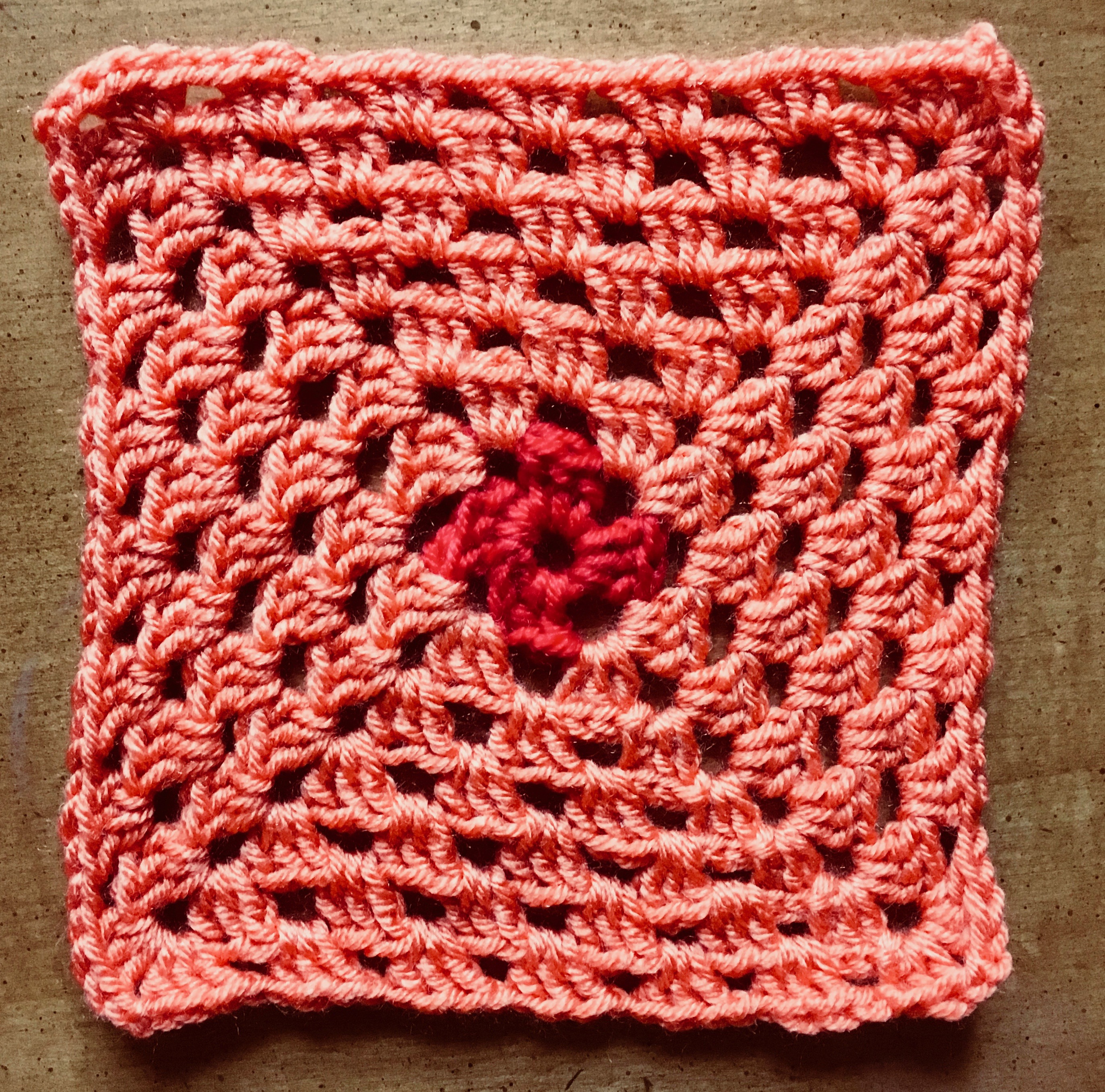 Single granny square with red center and orange outward layers (7 rows in total).