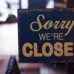 This image shows a sign that reads "Sorry we're closed" against a dark and shadowy background.