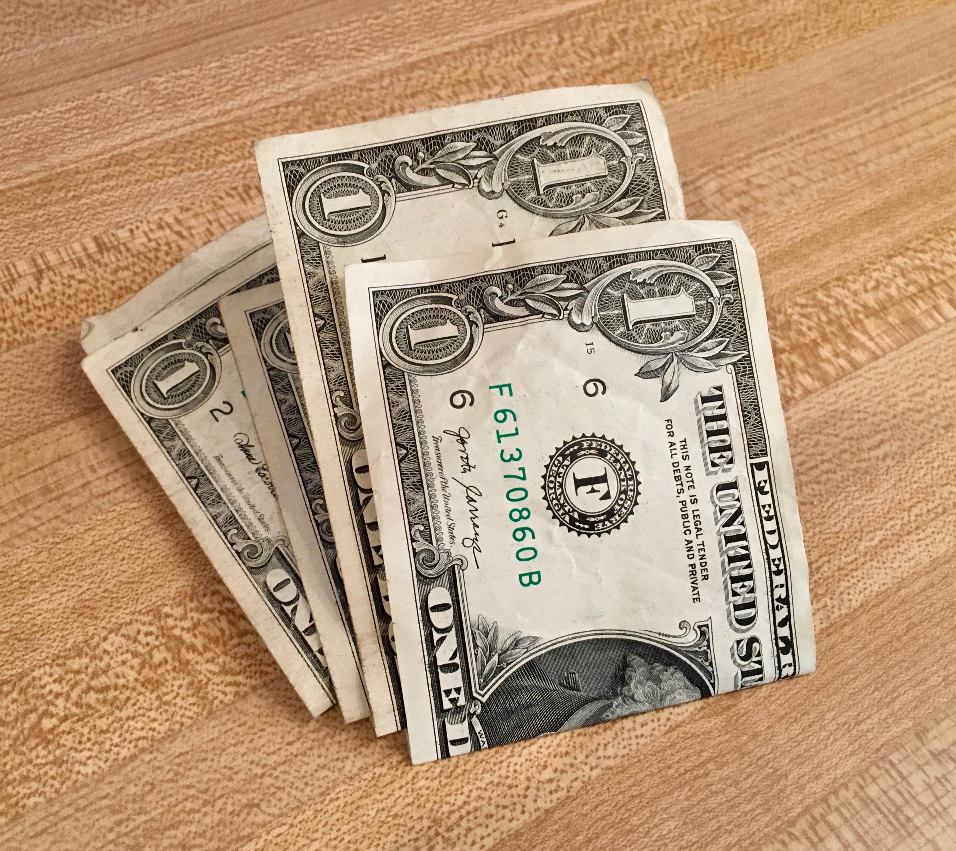 This image shows a stack of $1 bills folded in half on top of a brown countertop.
