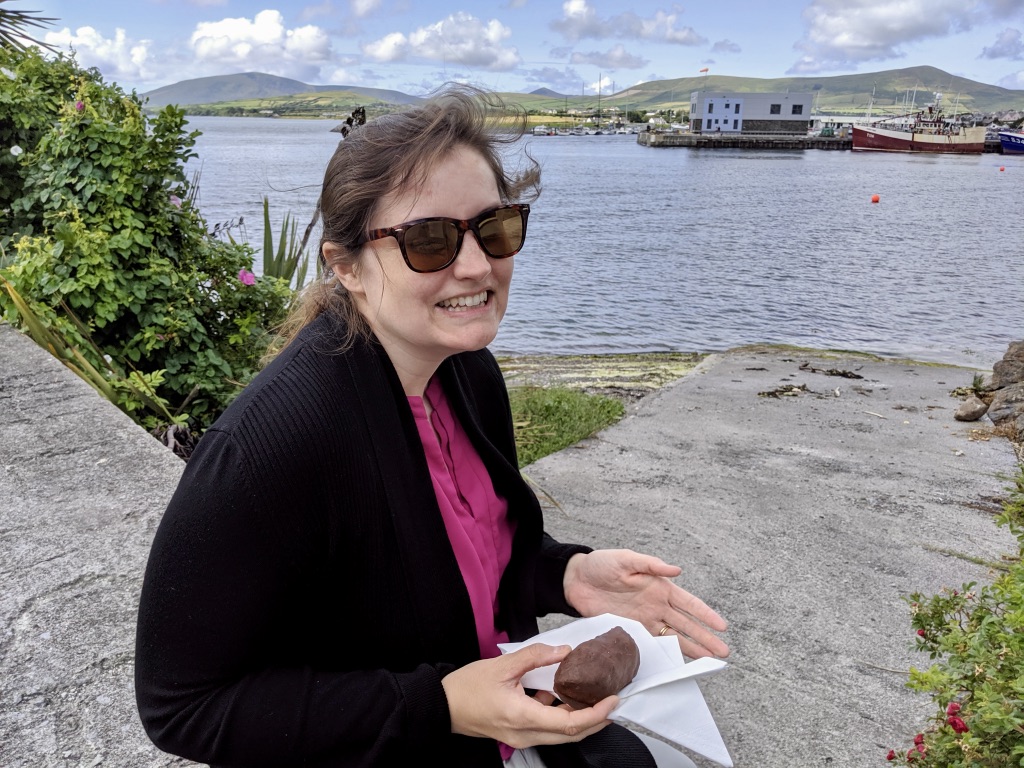 Beth eating a vegan mounds bar (chocolate and coconut) at the Dingle Harbor in County Kerry, Ireland.