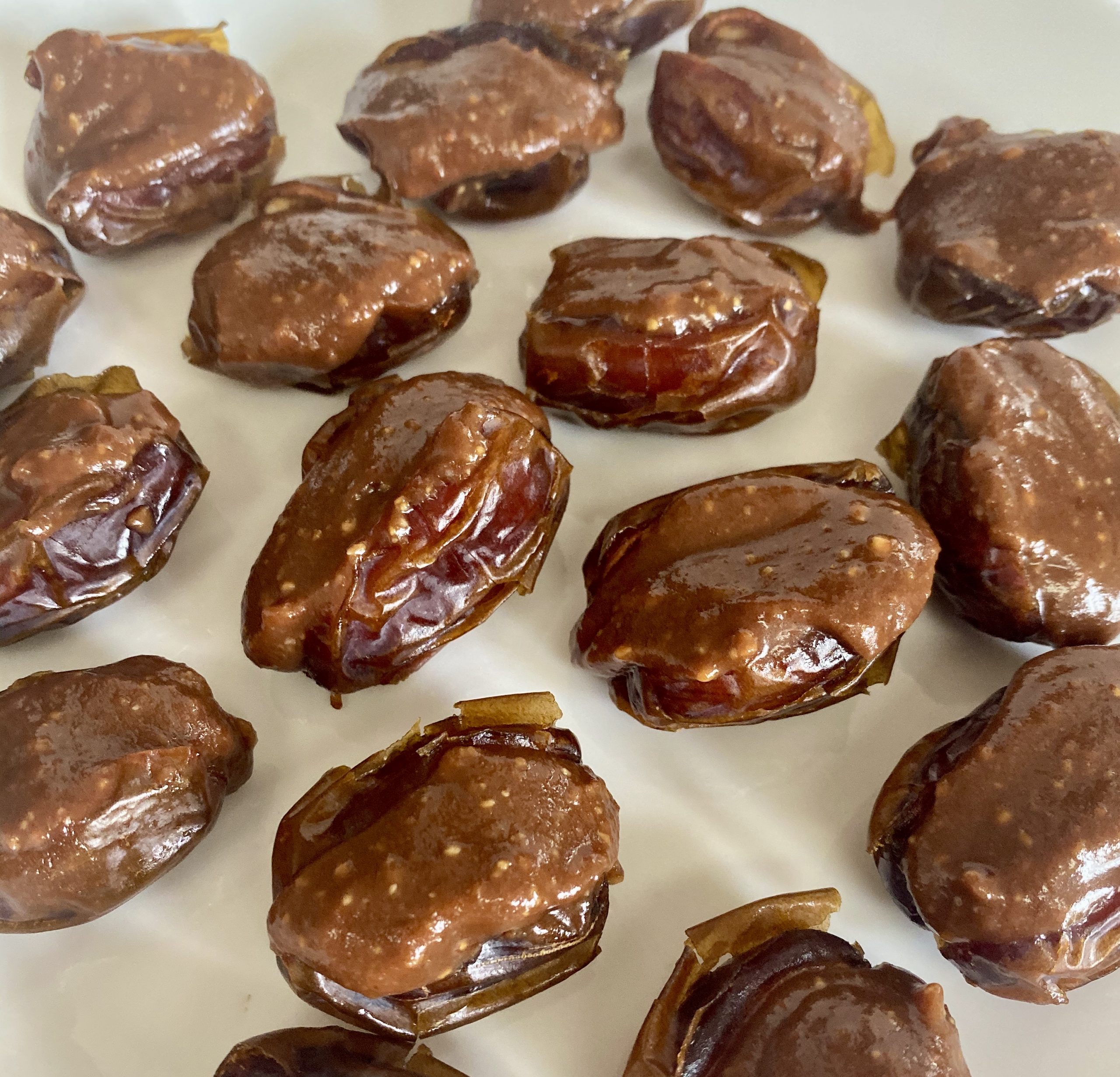 Vegan and gluten-free stuffed dates ready to eat, scattered across a serving plate: stuffed with a creamy mixture of chocolate, peanut butter, and coconut cream.