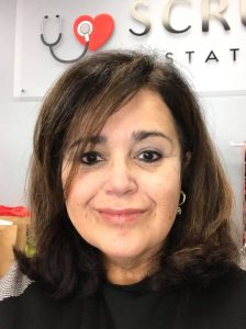 This image shows Ileana Rodriguez in front of the Scrubs Station sign (stethoscope and heart).