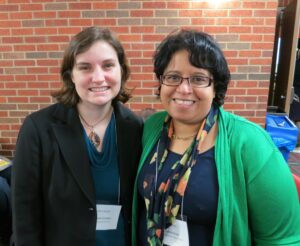 This photo from the 2014 Watson Conference shows the two of us—Beth Godbee (left) and Rasha Diab (right)—standing side-by-side; wearing a mix of blue, black, and green; in front of a brick wall.