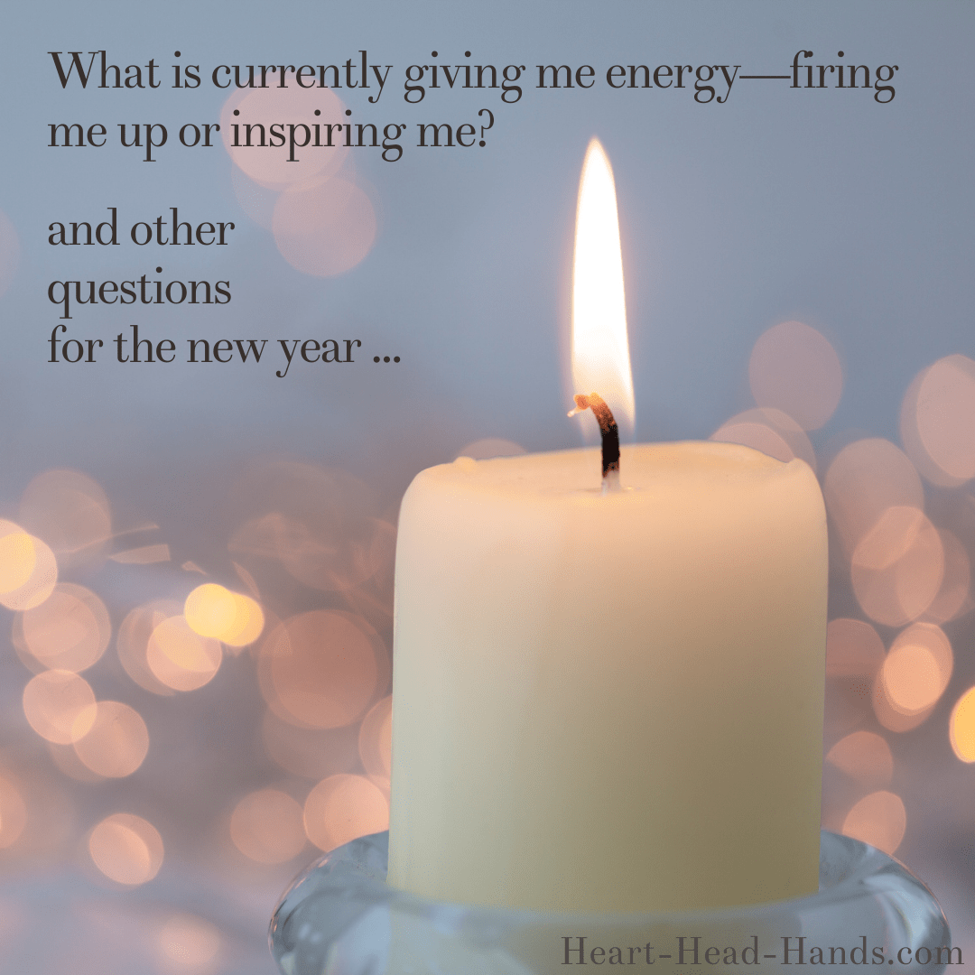 This image reads “What is currently giving me energy—firing me up or inspiring me? and other questions for the new year …” against a light blue-gray background. A cream-colored candle and flame appear with pink-peach glowing dots. Attribution to Heart-Head-Hands.com appears in the lower right-hand corner.