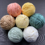 seven balls of yarn (in shades of yellow, orange, cream, green, and teal) for my current crochet project