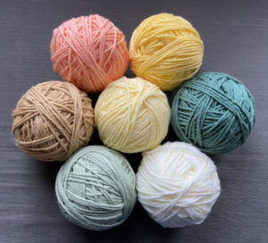 seven balls of yarn (in shades of yellow, orange, cream, green, and teal) for my current crochet project
