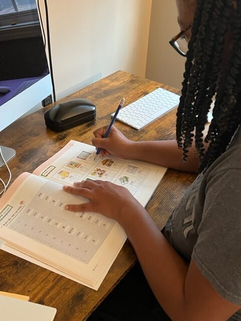 Candace Epps-Robertson studying Korean, writing in a workbook.