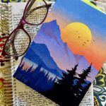 Image shows two journals (one open and one closed), along with a pair of glasses.