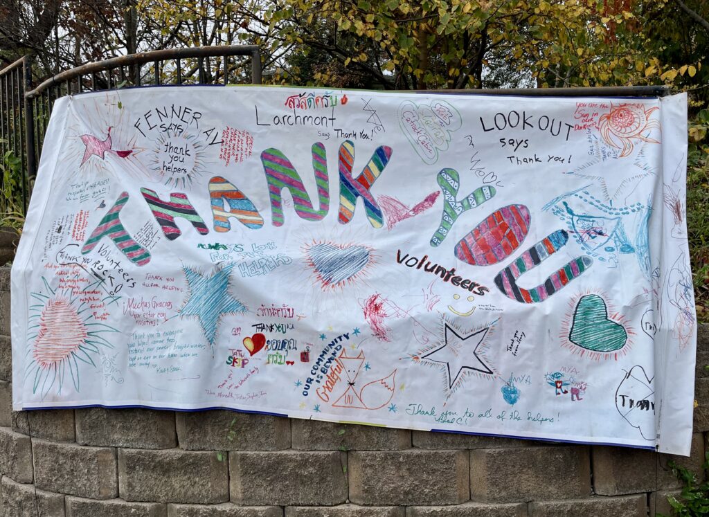 Colorful neighborhood sign that reads "THANK YOU volunteers" in large letters with lots of smaller text, hearts, and drawings. "Thank you to all of the helpers." and "Lookout says thank you!" and "Fenner Ave. says thank you helpers." and "Volunteers rock!" and more ...
