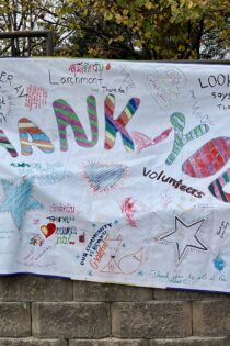 Colorful neighborhood sign that reads "THANK YOU volunteers" in large letters with lots of smaller text, hearts, and drawings. "Thank you to all of the helpers." and "Lookout says thank you!" and "Fenner Ave. says thank you helpers." and "Volunteers rock!" and more ...