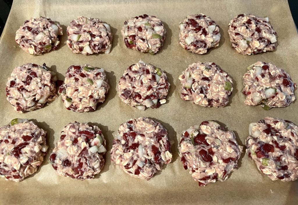 A tray lined with brown parchment paper is covered with 3 rows of veggie burgers with 5 in each row that are ready to be cooked.