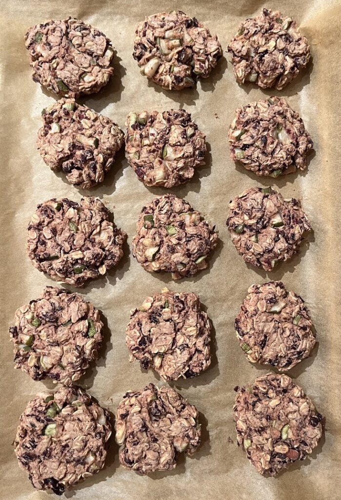 A tray lined with brown parchment paper is covered with 5 rows of veggie burgers with 3 in each row that have been cooked.
